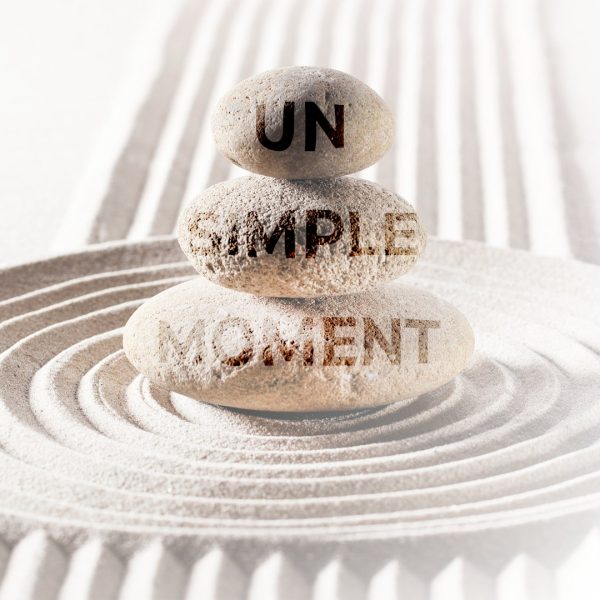 Pierres empilées avec l’inscription “Un Simple Moment”, illustrant le soin SPA et Hammam proposé par le Centre Naxane pour une relaxation profonde.