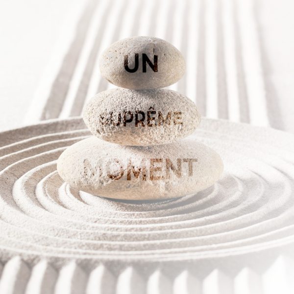 Pierres empilées avec l’inscription “Un Suprême Moment”, symbolisant le soin combinant SPA, Hammam, gommage, modelage californien et nettoyage de peau au Centre Naxane, pour une détente et une purification en profondeur.